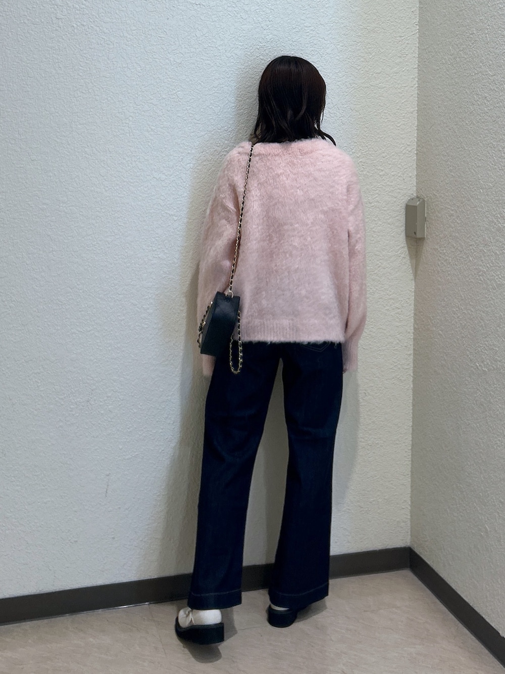 ピンク系のニット/セーター、ブルー系のデニムパンツ、ブラック系のショルダーバッグを着用したレディースの秋コーディネートの3枚目の写真