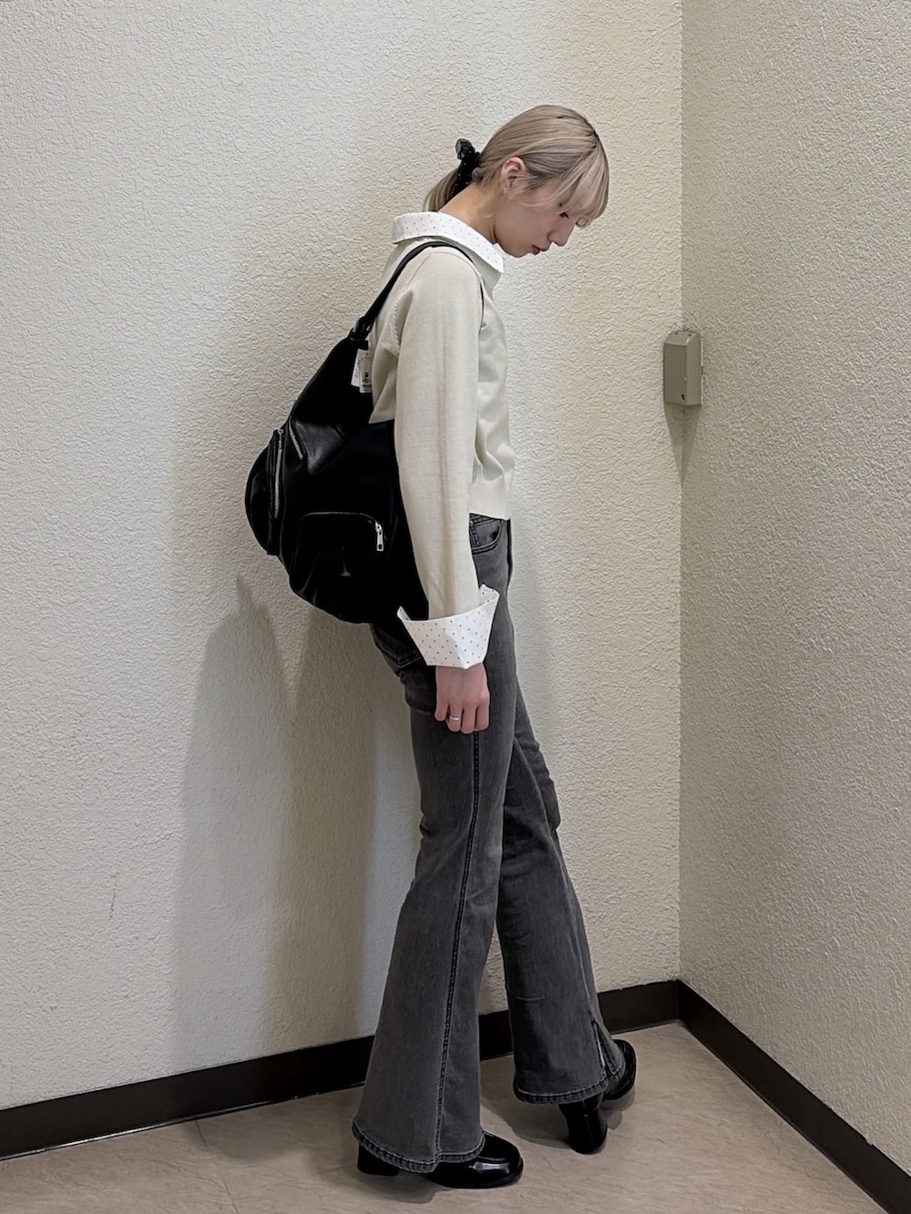 ブラック系のデニムパンツ、ブラック系のローファー、ベージュ系のニット/セーターを着用したレディースの春コーディネートの2枚目の写真