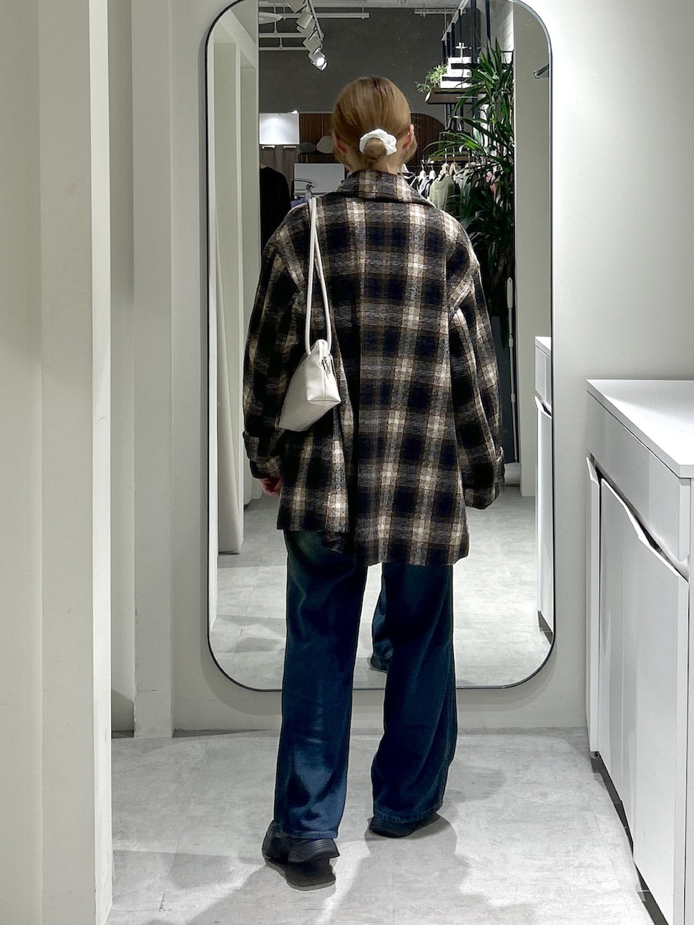 ホワイト系のスウェット、ブルー系のデニムパンツ、ブラウン系のピーコートを着用したレディースの秋コーディネートの4枚目の写真