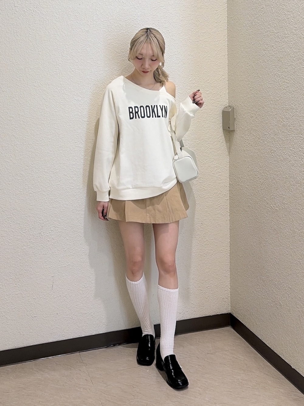 ホワイト系のスウェット、ベージュ系のスカート、ブラック系のローファーを着用したレディースの春コーディネートの4枚目の写真