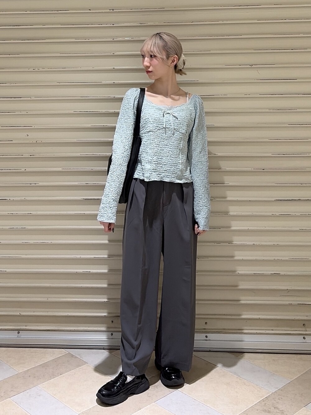 グレー系のスラックス、ブルー系のTシャツ/カットソー、ブラック系のトートバッグを着用したレディースの春コーディネートの7枚目の写真