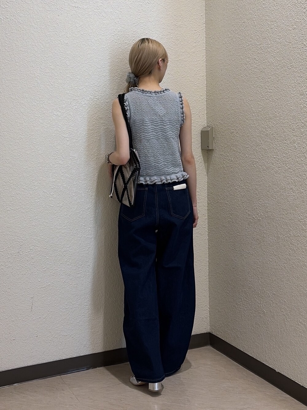 ブルー系のニット/セーター、ブルー系のデニムパンツ、ブラック系のトートバッグを着用したレディースの夏コーディネートの3枚目の写真