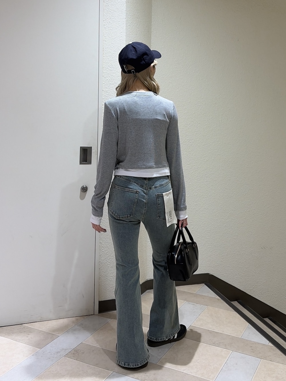 グレー系のTシャツ/カットソー、ブルー系のデニムパンツ、ブラック系のハンドバッグを着用したレディースの春コーディネートの3枚目の写真