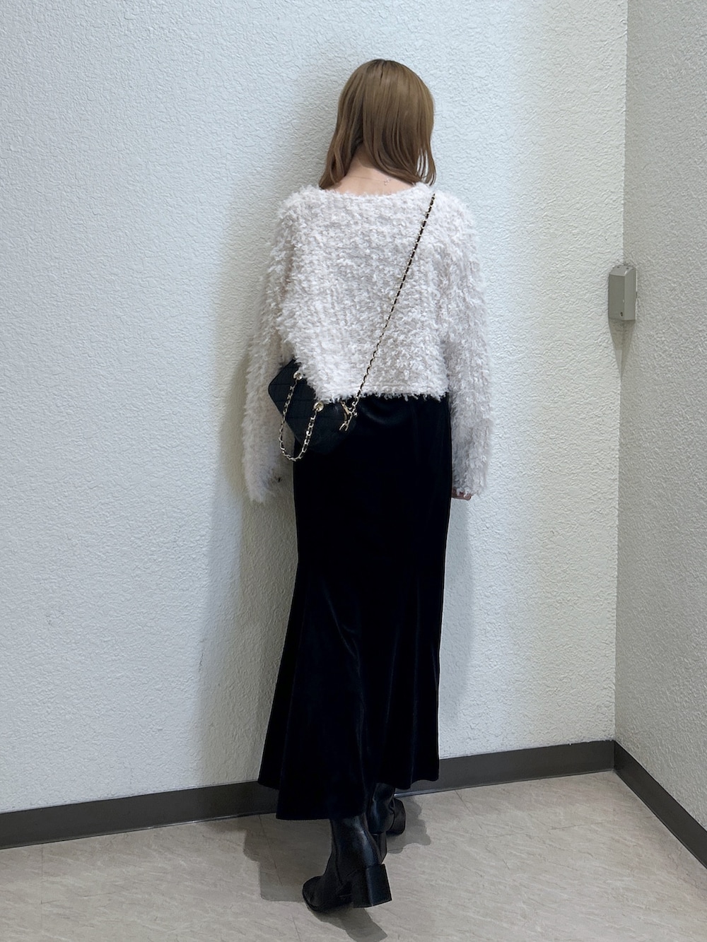 ブラック系のスカート、ブラック系のブーツ、ブラック系のショルダーバッグを着用したレディースの秋コーディネートの3枚目の写真