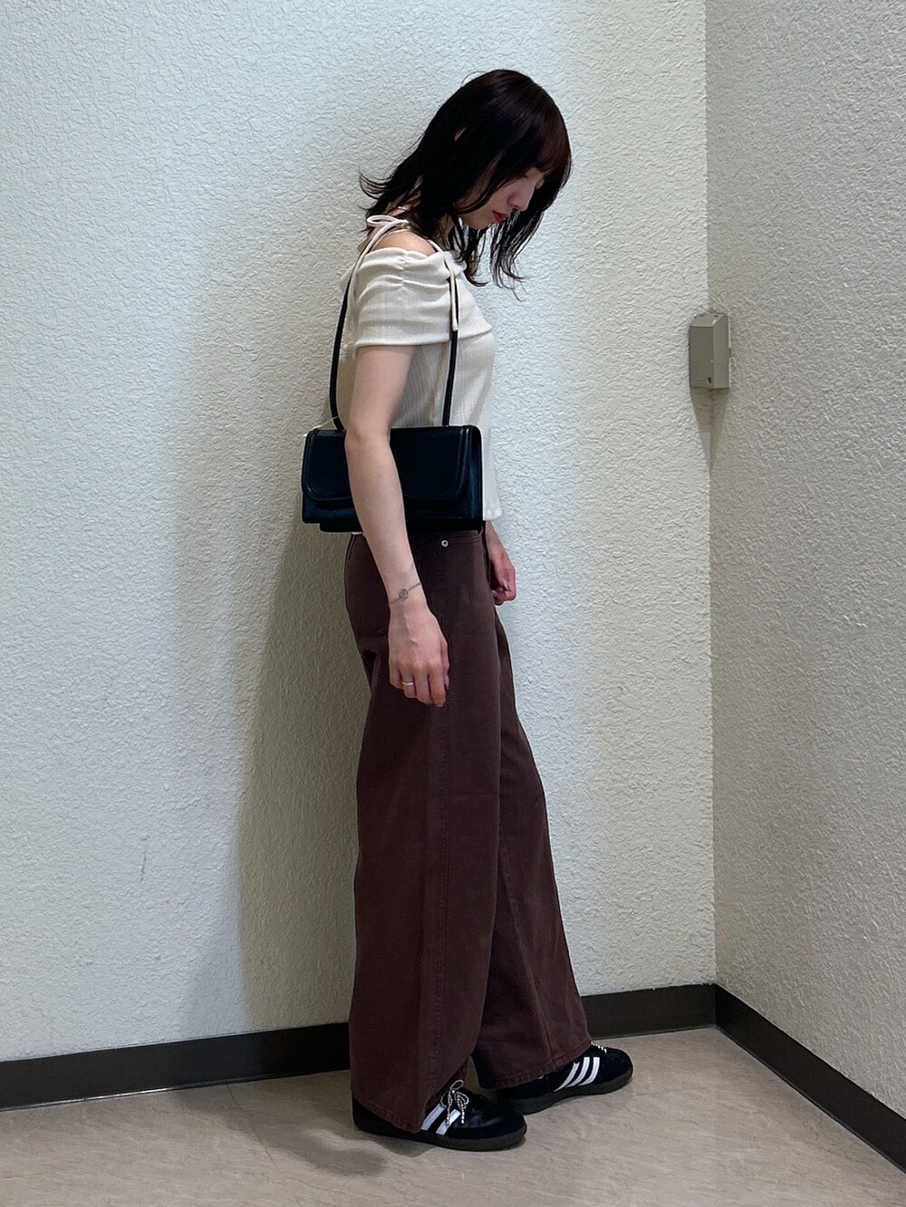 ホワイト系のTシャツ/カットソー、ブラウン系のデニムパンツ、ブラック系のショルダーバッグを着用したレディースの夏コーディネートの3枚目の写真