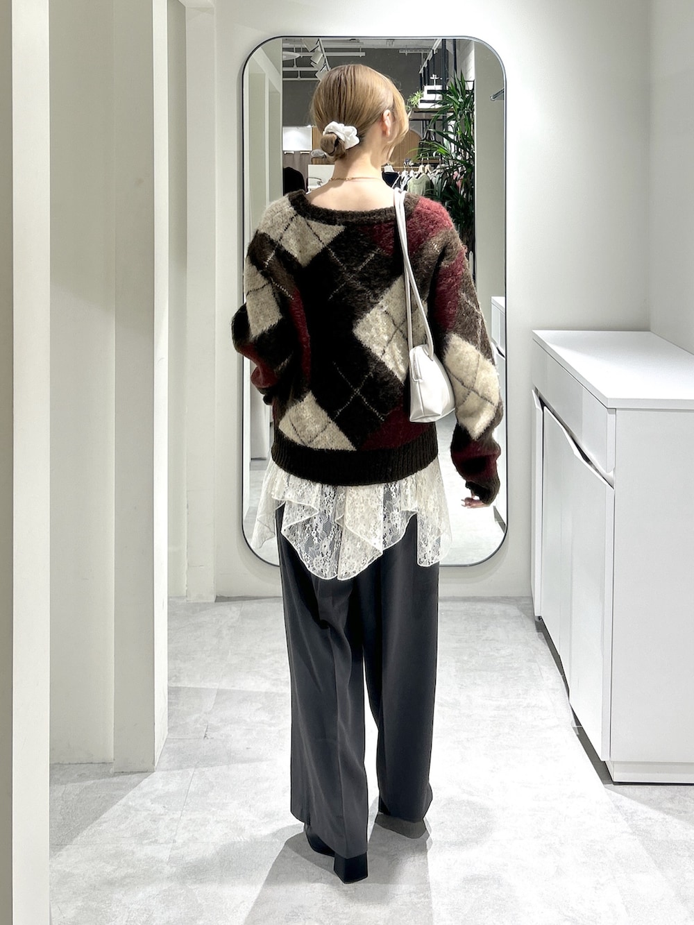 グレー系のスラックス、ブラック系のブーツ、ホワイト系のスカートを着用したレディースの秋コーディネートの3枚目の写真