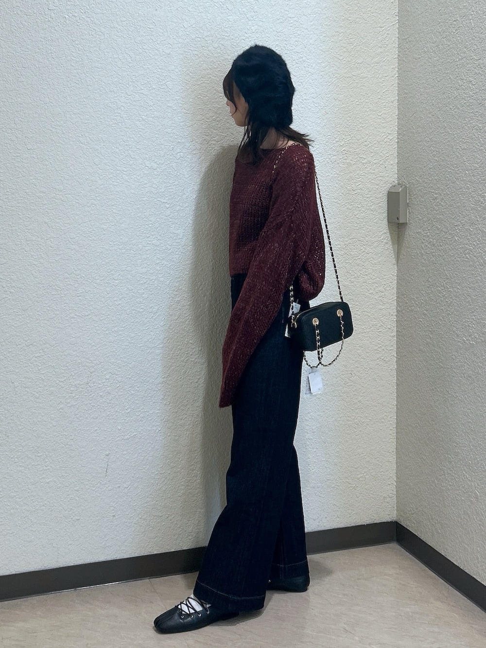 レッド系のニット/セーター、ブルー系のデニムパンツ、ブラック系のショルダーバッグを着用したレディースの秋コーディネートの2枚目の写真