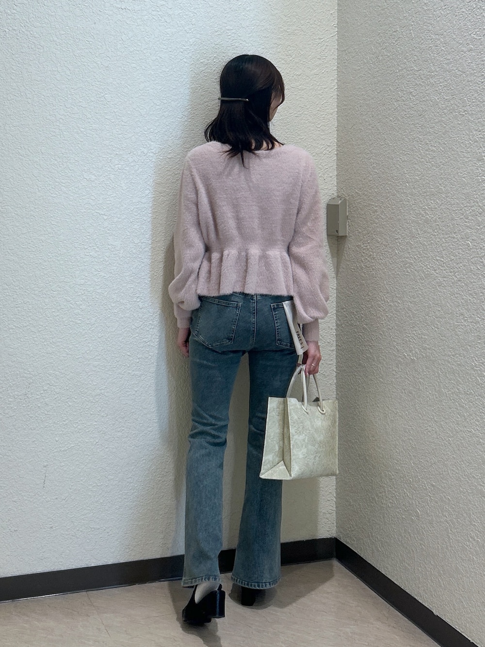 ピンク系のニット/セーター、ブルー系のデニムパンツ、ホワイト系のトートバッグを着用したレディースの秋コーディネートの2枚目の写真