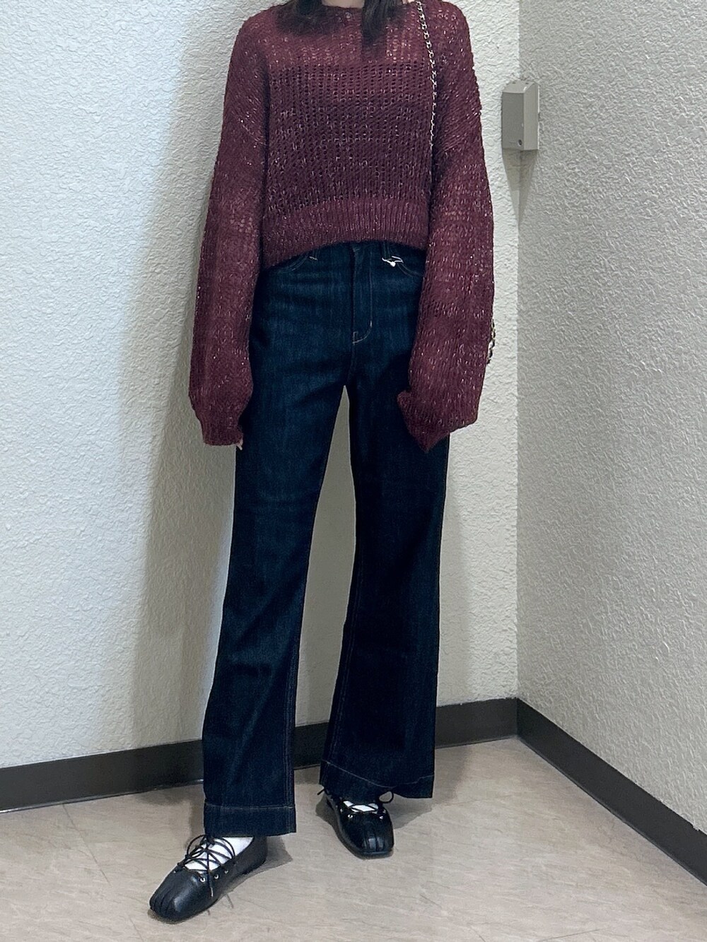 レッド系のニット/セーター、ブルー系のデニムパンツ、ブラック系のショルダーバッグを着用したレディースの秋コーディネートの4枚目の写真