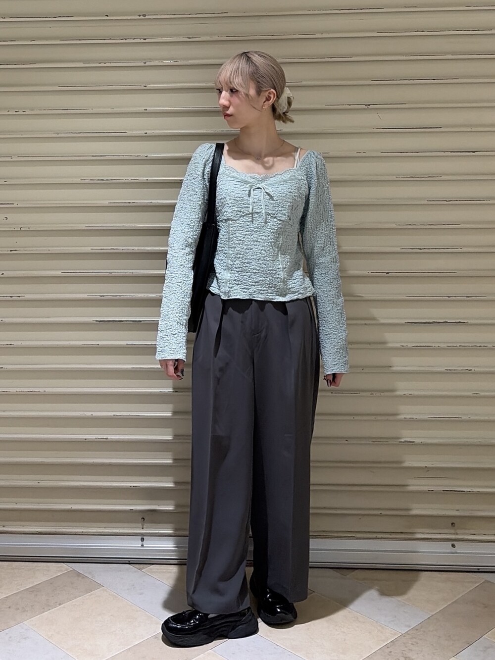 グレー系のスラックス、ブルー系のTシャツ/カットソー、ブラック系のトートバッグを着用したレディースの春コーディネートの6枚目の写真