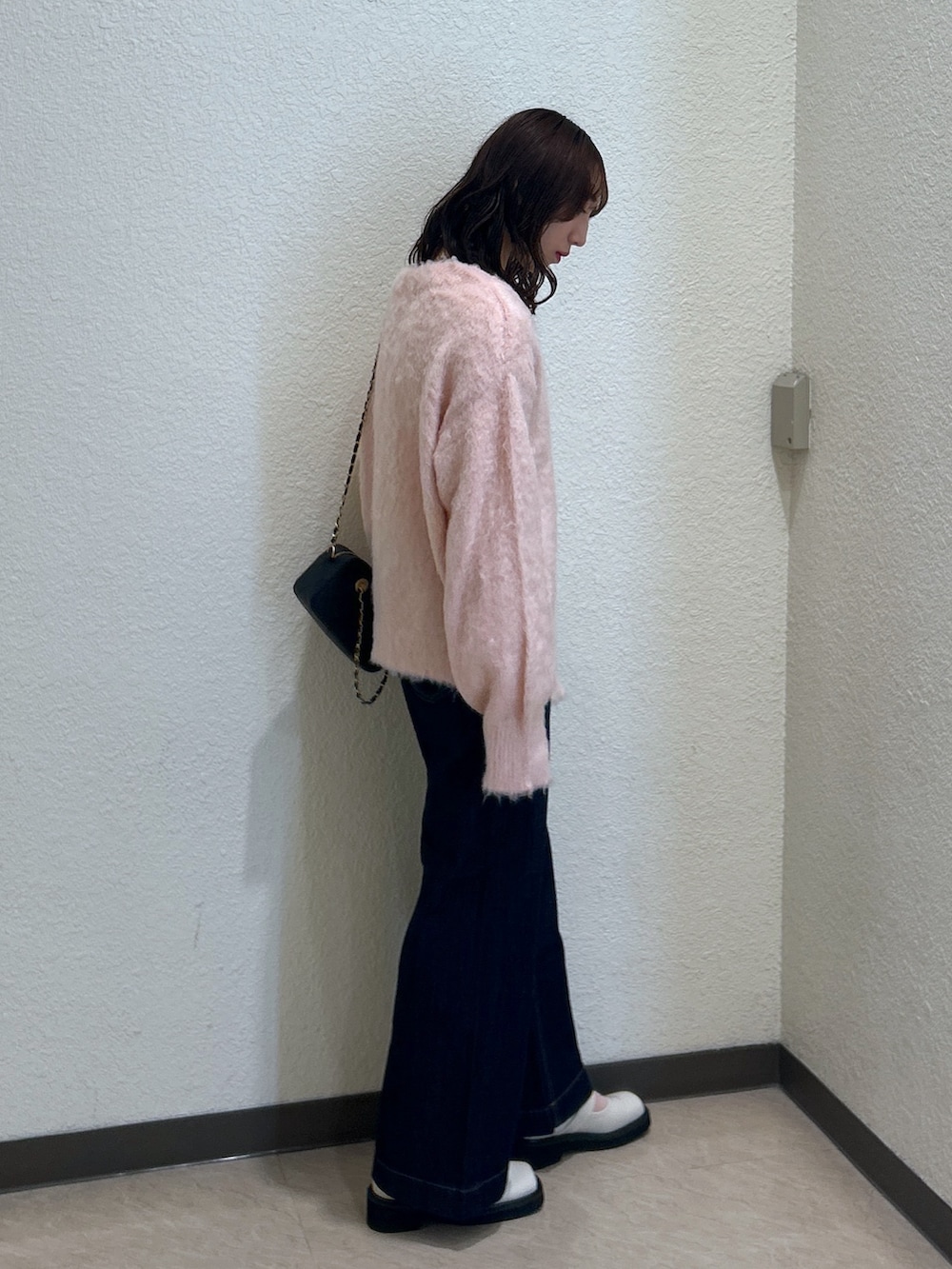 ピンク系のニット/セーター、ブルー系のデニムパンツ、ブラック系のショルダーバッグを着用したレディースの秋コーディネートの2枚目の写真