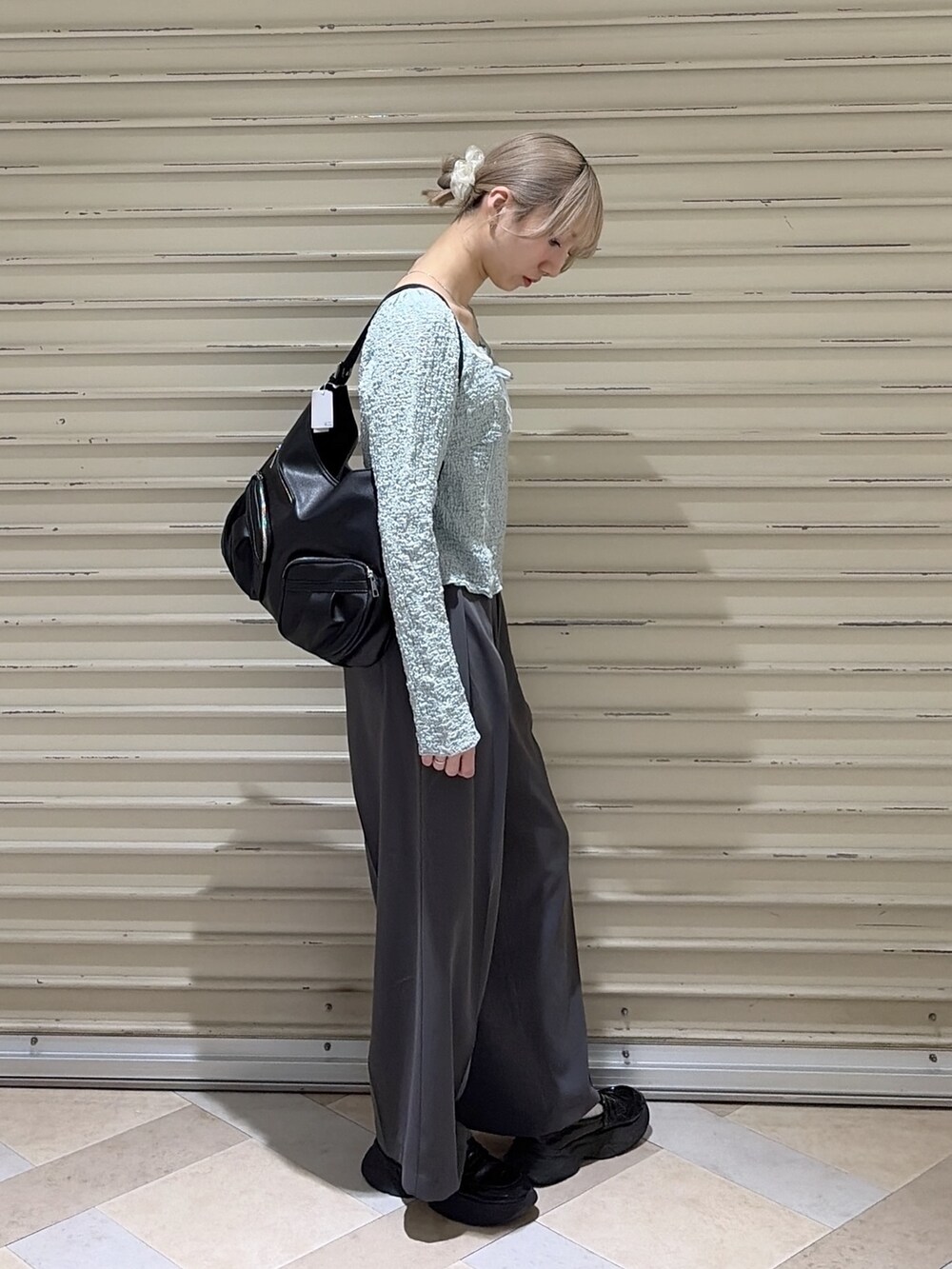 グレー系のスラックス、ブルー系のTシャツ/カットソー、ブラック系のトートバッグを着用したレディースの春コーディネートの4枚目の写真
