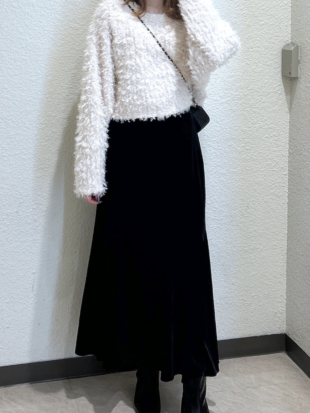 ブラック系のスカート、ブラック系のブーツ、ブラック系のショルダーバッグを着用したレディースの秋コーディネートの4枚目の写真