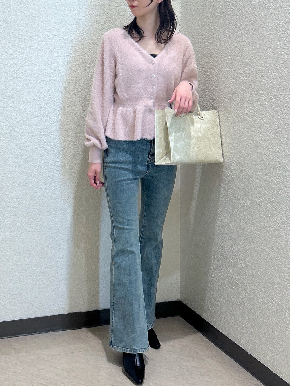 ピンク系のニット/セーター、ブルー系のデニムパンツ、ホワイト系のトートバッグを着用したレディースの秋コーディネートの4枚目の写真