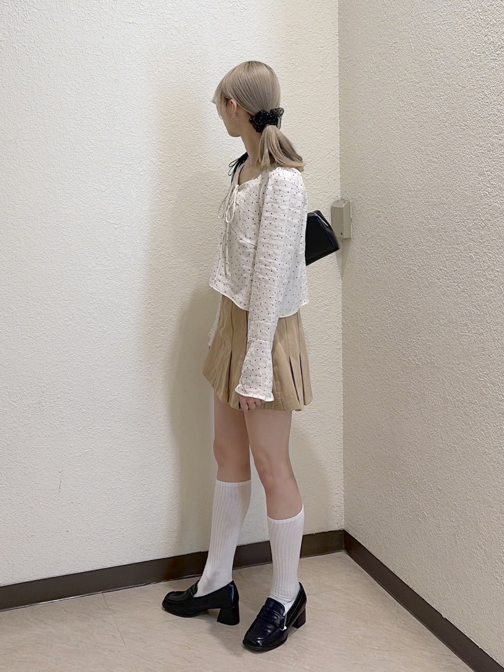 ベージュ系のスカート、ブラック系のローファー、ホワイト系のシャツ/ブラウスを着用したレディースの春コーディネートの2枚目の写真