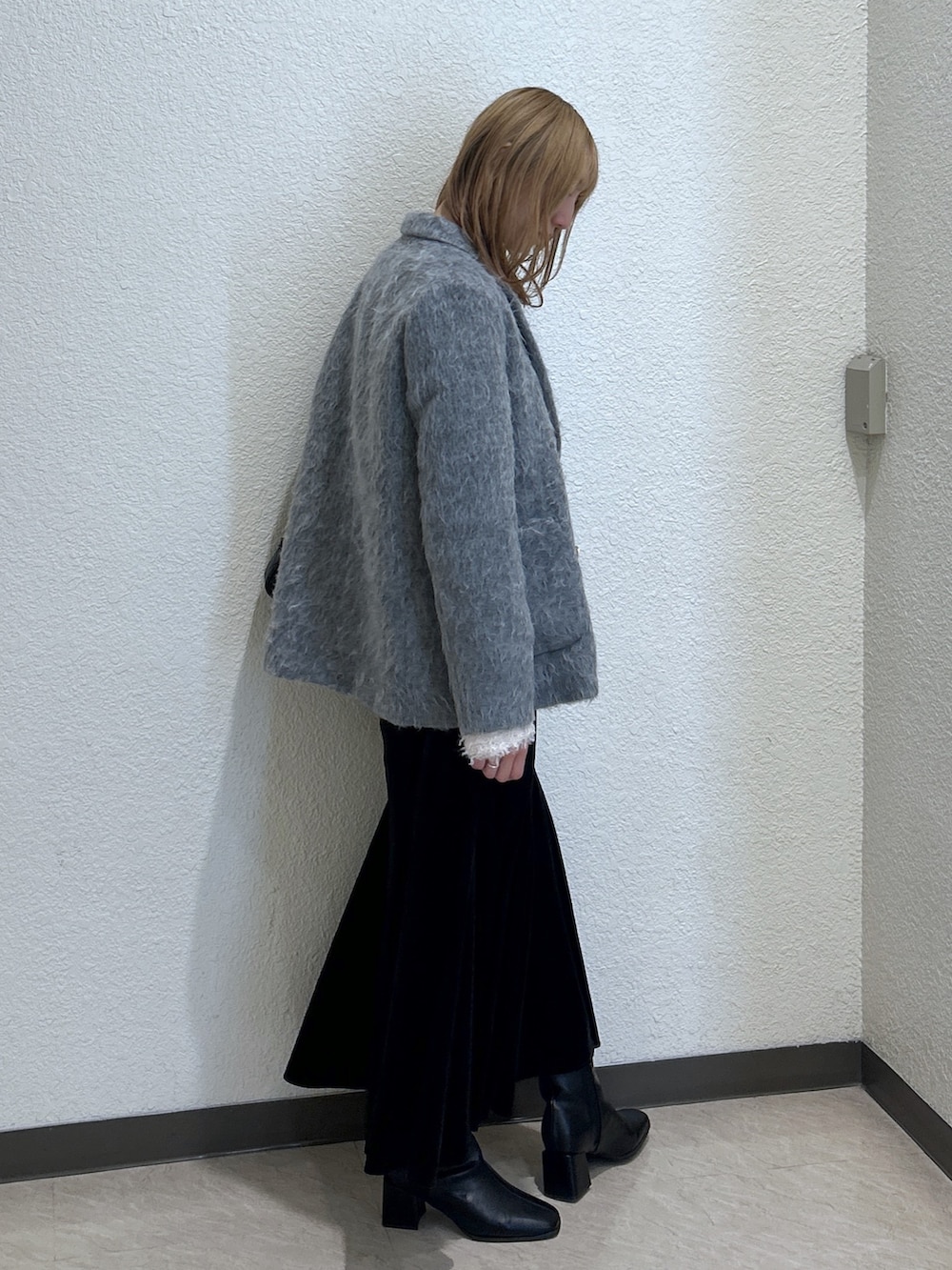 グレー系のチェスターコート、ホワイト系のTシャツ/カットソー、ブラック系のスカートを着用したレディースの秋コーディネートの2枚目の写真