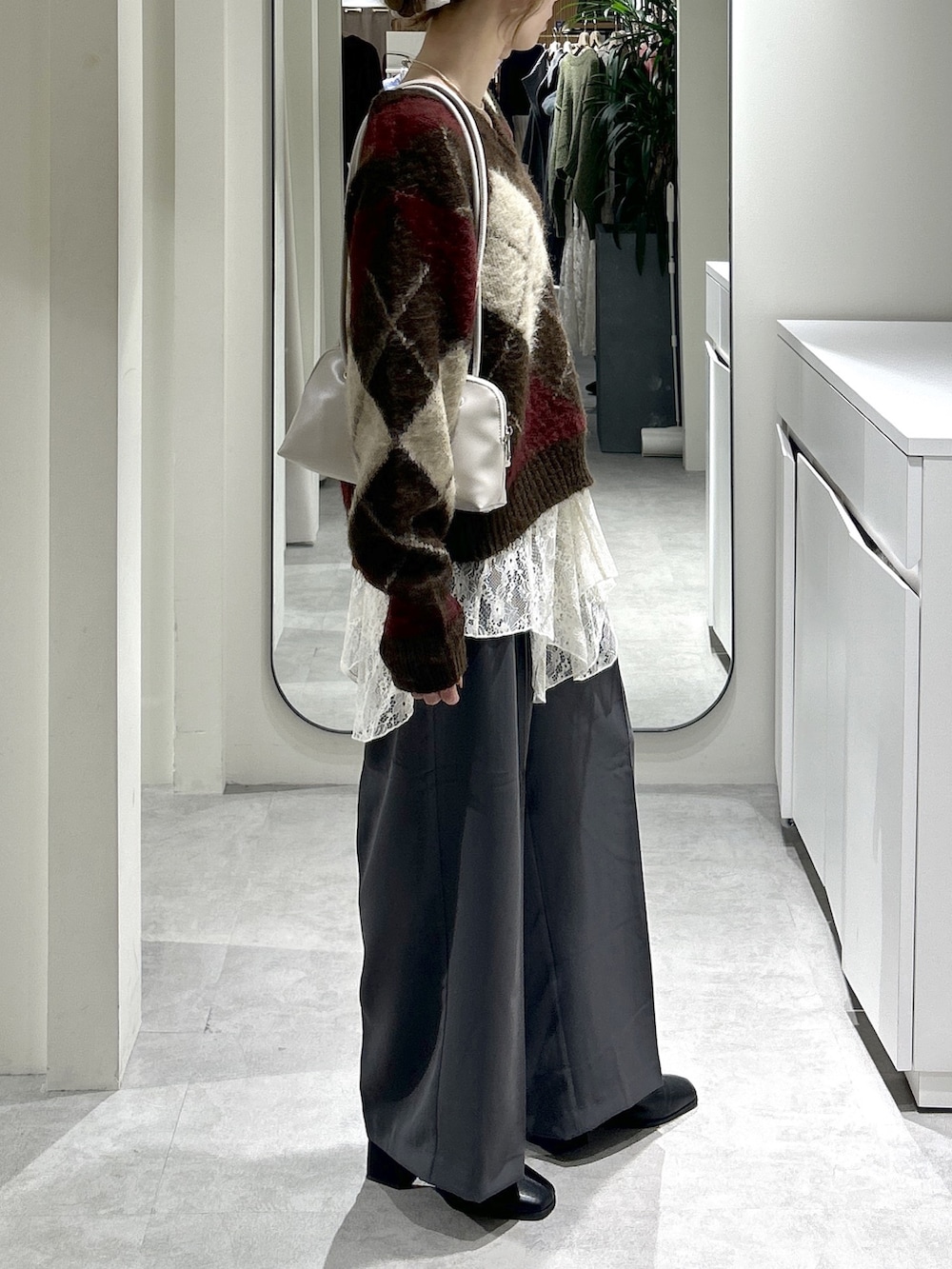 グレー系のスラックス、ブラック系のブーツ、ホワイト系のスカートを着用したレディースの秋コーディネートの6枚目の写真