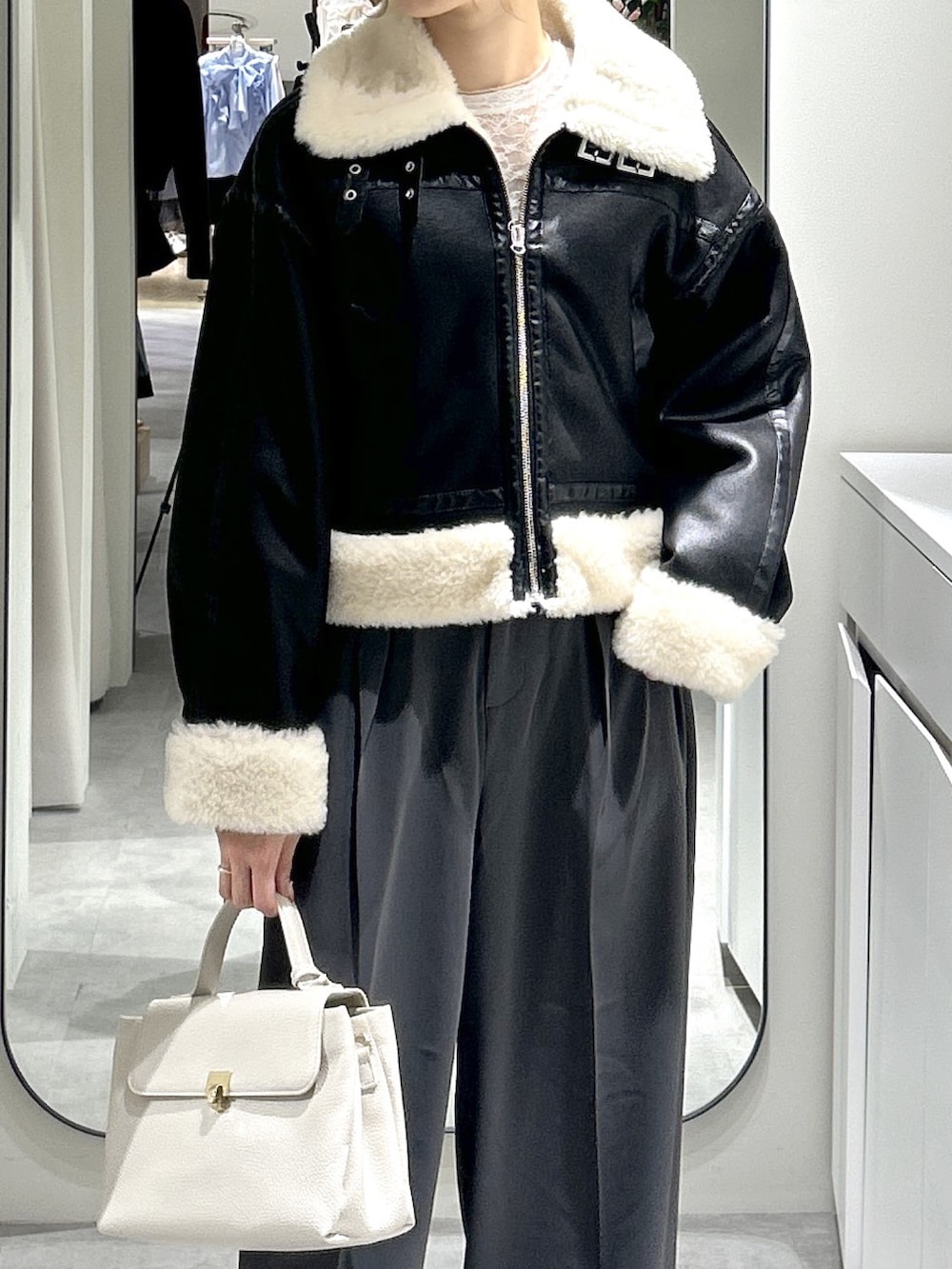 ブラック系のブルゾン、ブラック系のブーツ、グレー系のスラックスを着用したレディースの秋コーディネートの2枚目の写真