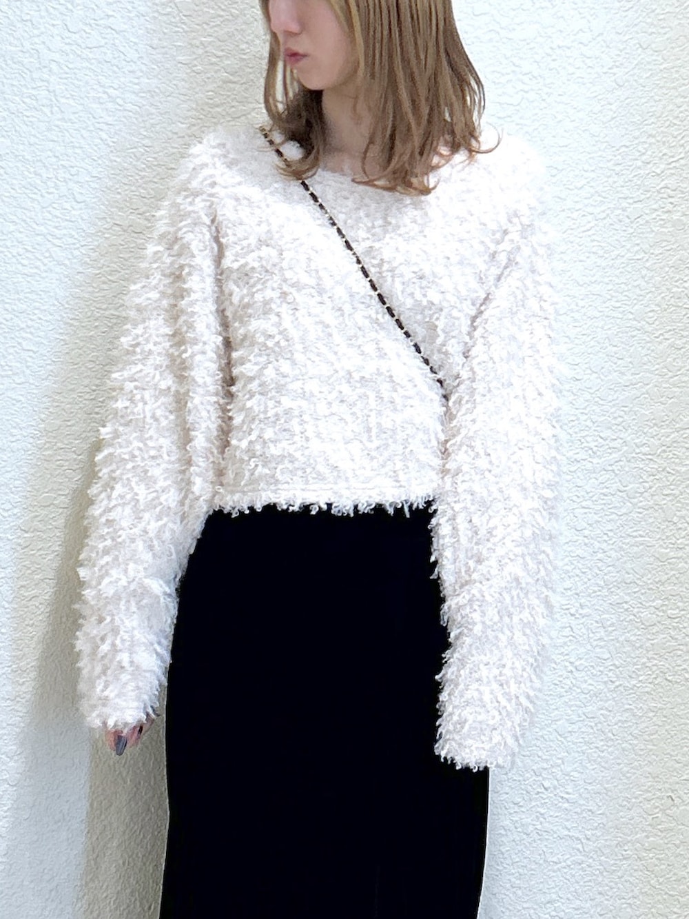 ブラック系のスカート、ブラック系のブーツ、ブラック系のショルダーバッグを着用したレディースの秋コーディネートの5枚目の写真