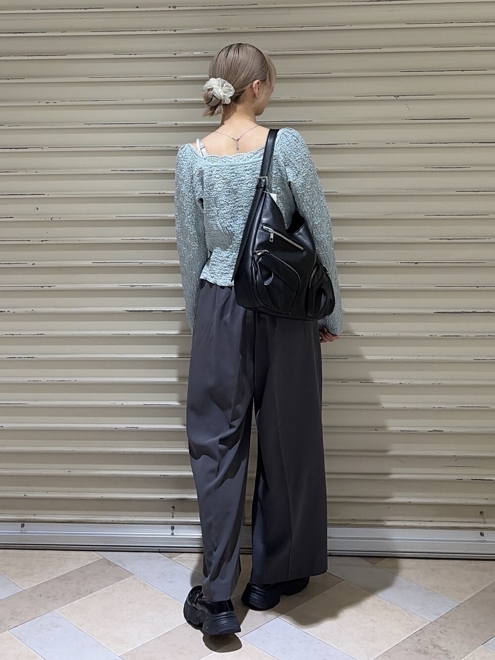 グレー系のスラックス、ブルー系のTシャツ/カットソー、ブラック系のトートバッグを着用したレディースの春コーディネートの3枚目の写真