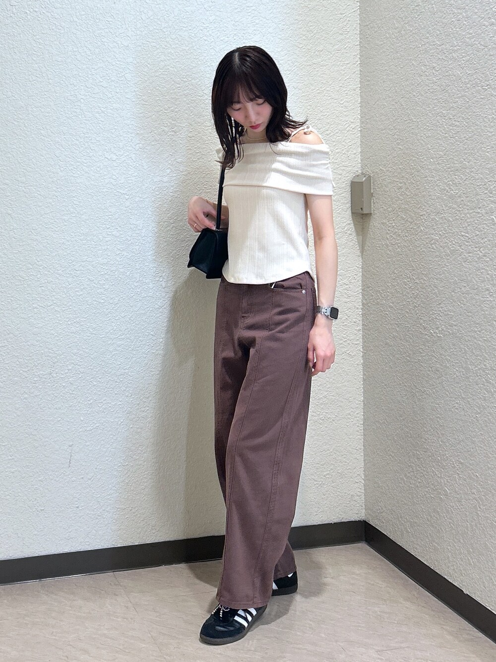 ホワイト系のTシャツ/カットソー、ブラウン系のデニムパンツ、ブラック系のショルダーバッグを着用したレディースの夏コーディネートの2枚目の写真