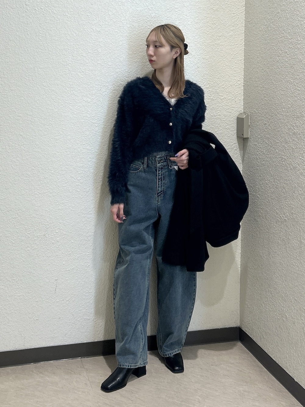 ブルー系のニット/セーター、ブラック系のステンカラーコート、ブラック系のブーツを着用したレディースの秋コーディネートの2枚目の写真