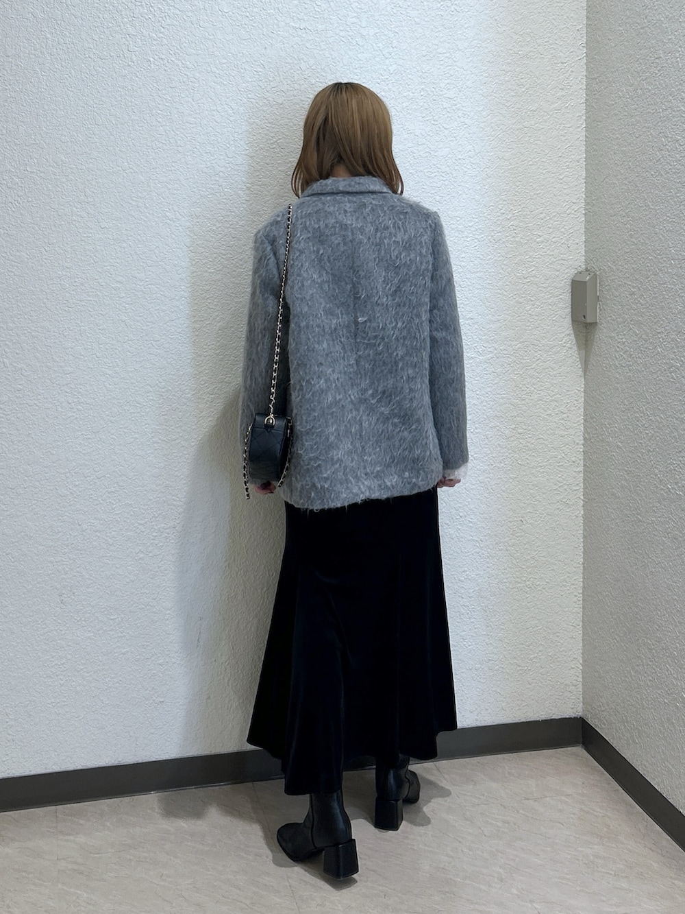 グレー系のチェスターコート、ホワイト系のTシャツ/カットソー、ブラック系のスカートを着用したレディースの秋コーディネートの3枚目の写真