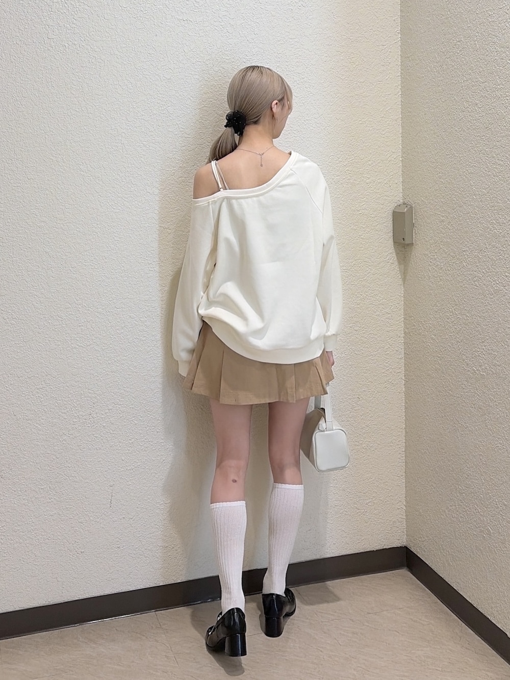 ホワイト系のスウェット、ベージュ系のスカート、ブラック系のローファーを着用したレディースの春コーディネートの2枚目の写真