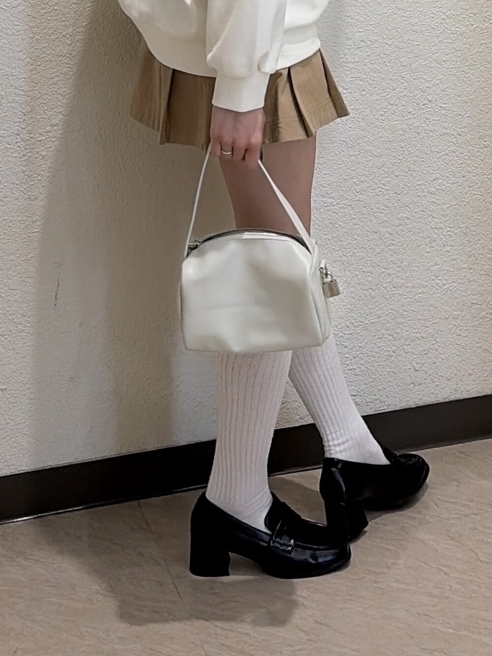 ホワイト系のスウェット、ベージュ系のスカート、ブラック系のローファーを着用したレディースの春コーディネートの5枚目の写真