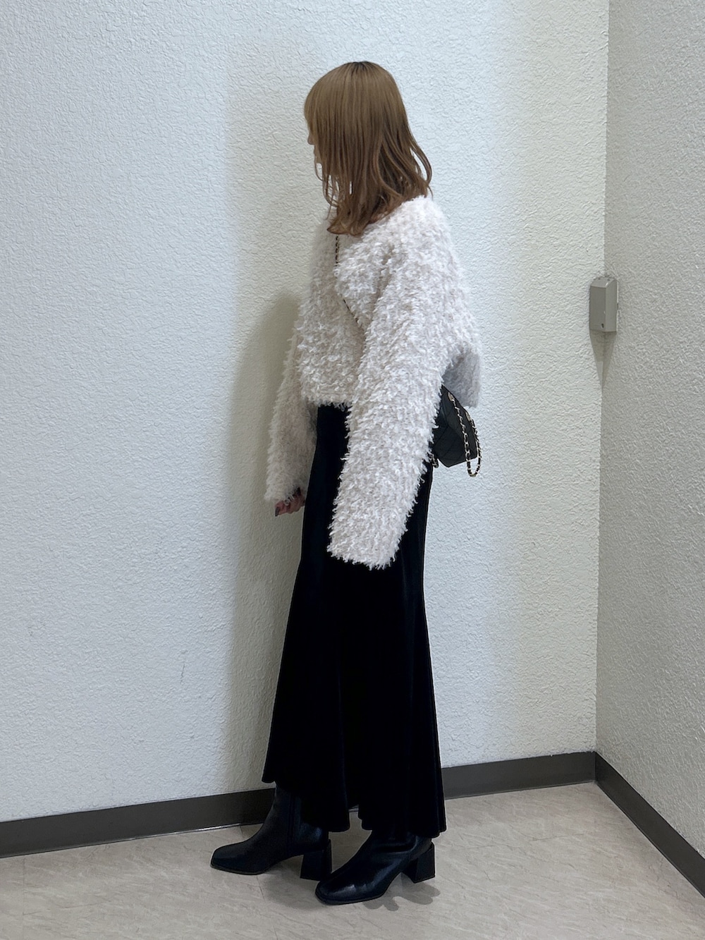 ブラック系のスカート、ブラック系のブーツ、ブラック系のショルダーバッグを着用したレディースの秋コーディネートの2枚目の写真