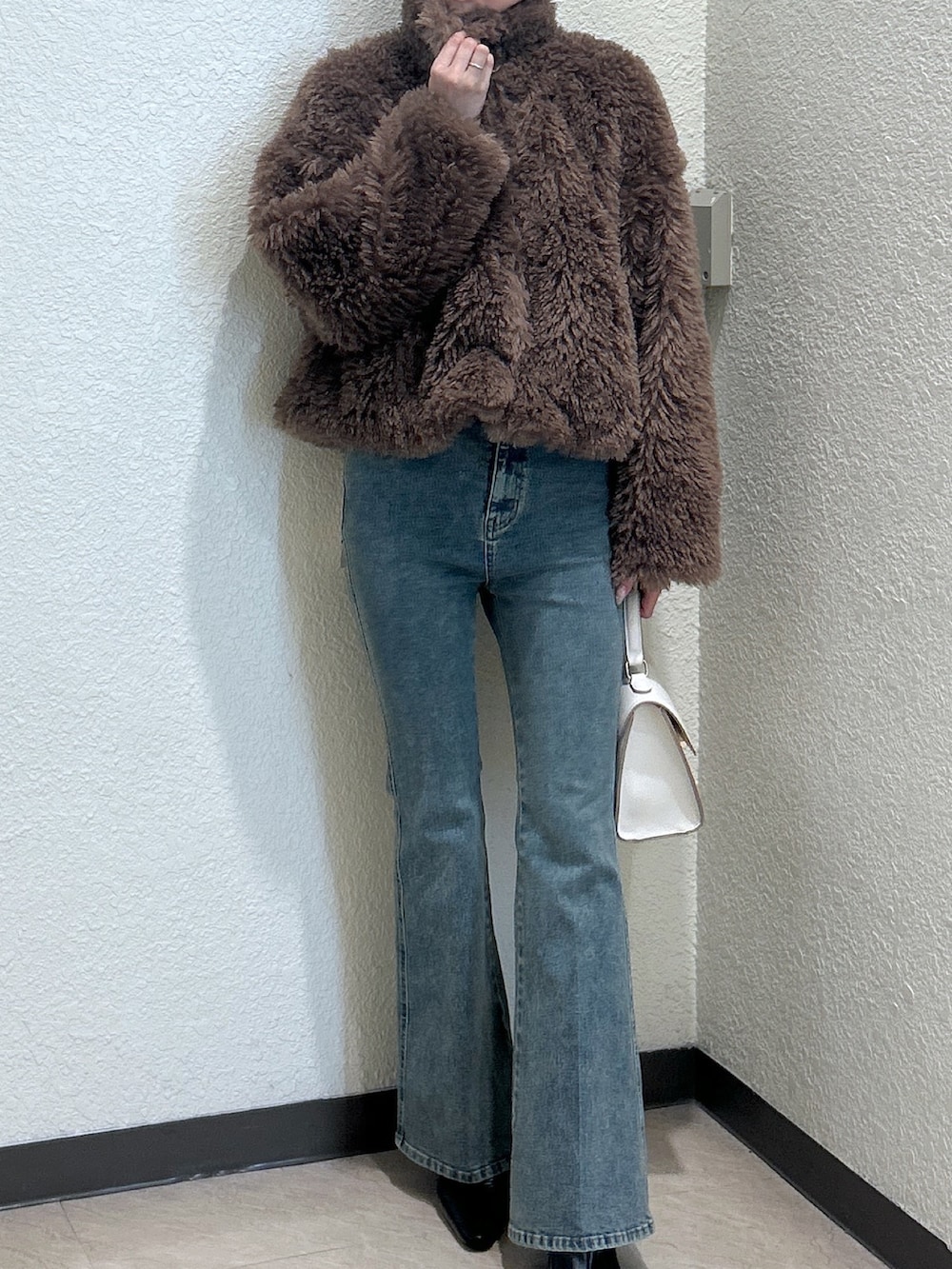 ホワイト系のトートバッグ、ブルー系のデニムパンツ、ブラック系のパンプスを着用したレディースの秋コーディネートの4枚目の写真