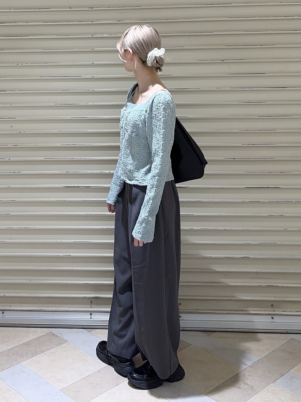 グレー系のスラックス、ブルー系のTシャツ/カットソー、ブラック系のトートバッグを着用したレディースの春コーディネートの2枚目の写真