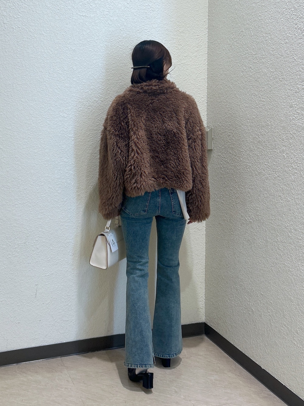 ホワイト系のトートバッグ、ブルー系のデニムパンツ、ブラック系のパンプスを着用したレディースの秋コーディネートの3枚目の写真