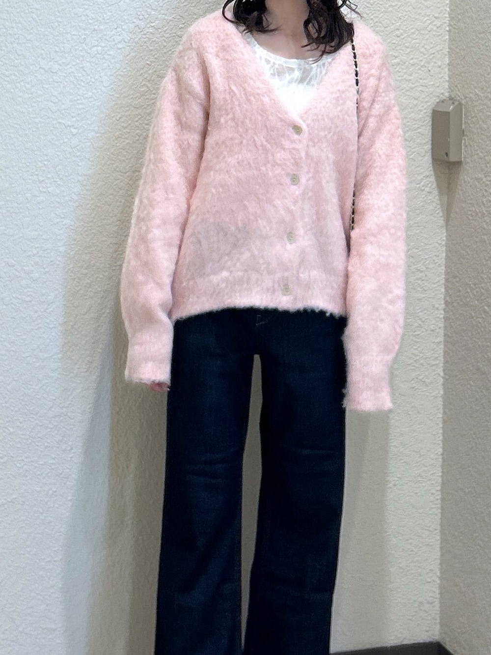 ピンク系のニット/セーター、ブルー系のデニムパンツ、ブラック系のショルダーバッグを着用したレディースの秋コーディネートの4枚目の写真