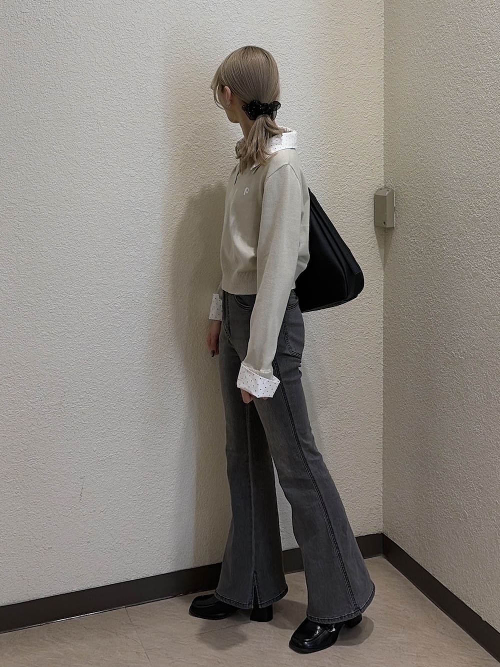 ブラック系のデニムパンツ、ブラック系のローファー、ベージュ系のニット/セーターを着用したレディースの春コーディネートの3枚目の写真