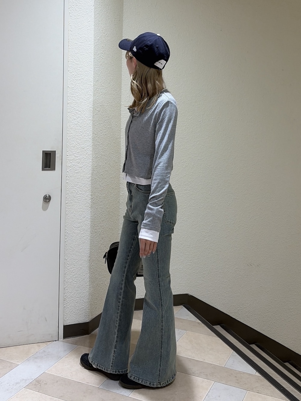 グレー系のTシャツ/カットソー、ブルー系のデニムパンツ、ブラック系のハンドバッグを着用したレディースの春コーディネートの2枚目の写真