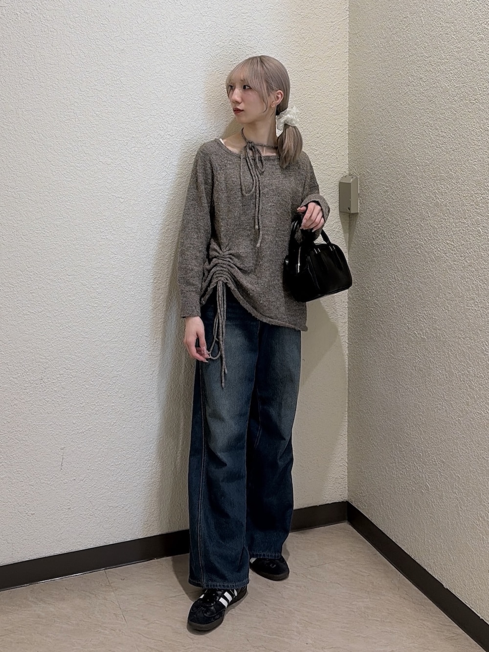 ブラウン系のニット/セーター、ブルー系のデニムパンツ、ブラック系のハンドバッグを着用したレディースの冬コーディネートの2枚目の写真