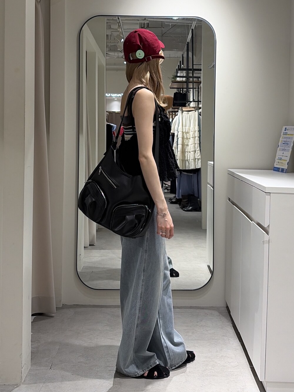 ブラック系のシャツ/ブラウス、ブルー系のニット/セーター、ブルー系のデニムパンツを着用したレディースの夏コーディネートの2枚目の写真
