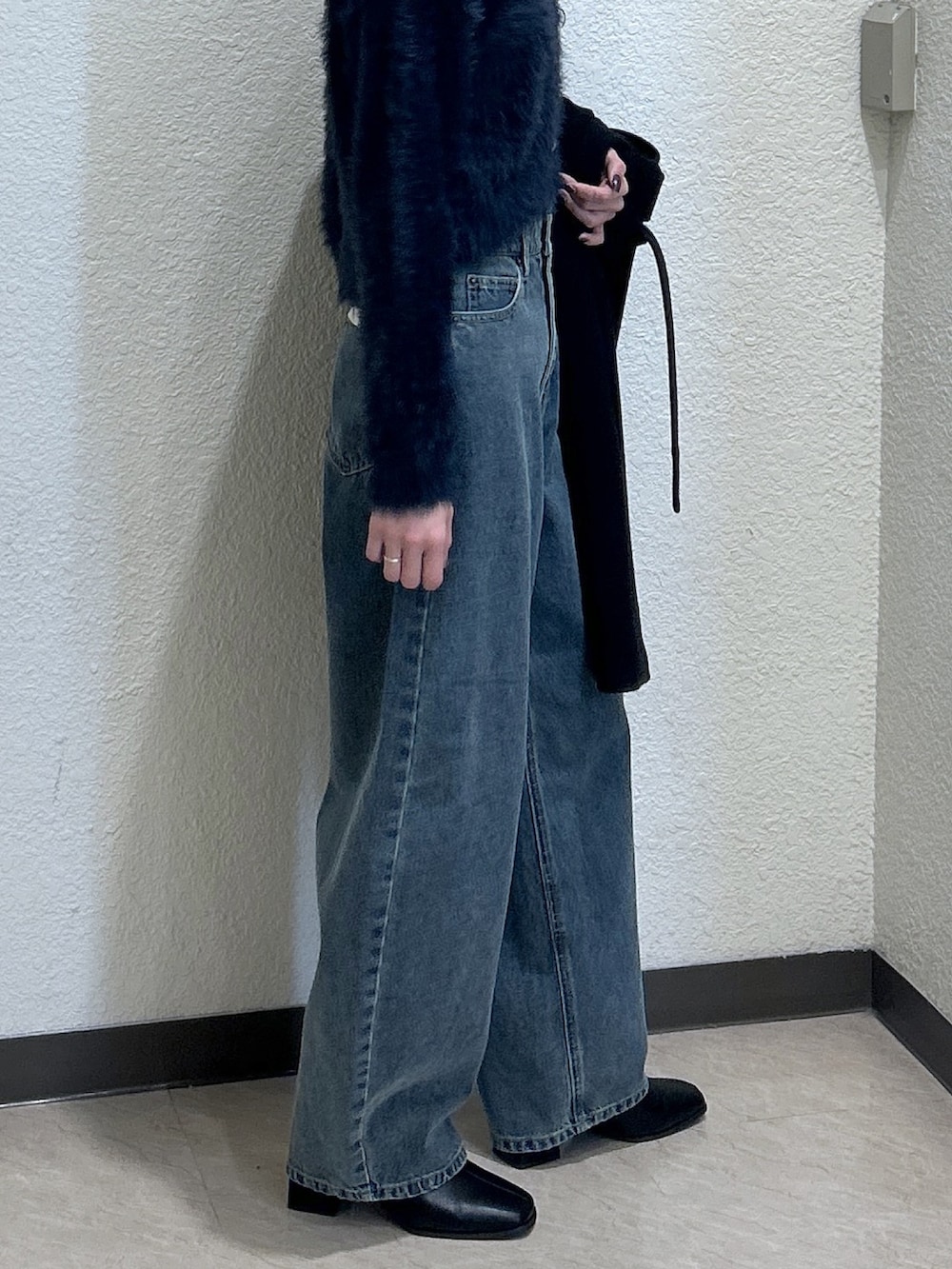 ブルー系のニット/セーター、ブラック系のステンカラーコート、ブラック系のブーツを着用したレディースの秋コーディネートの4枚目の写真