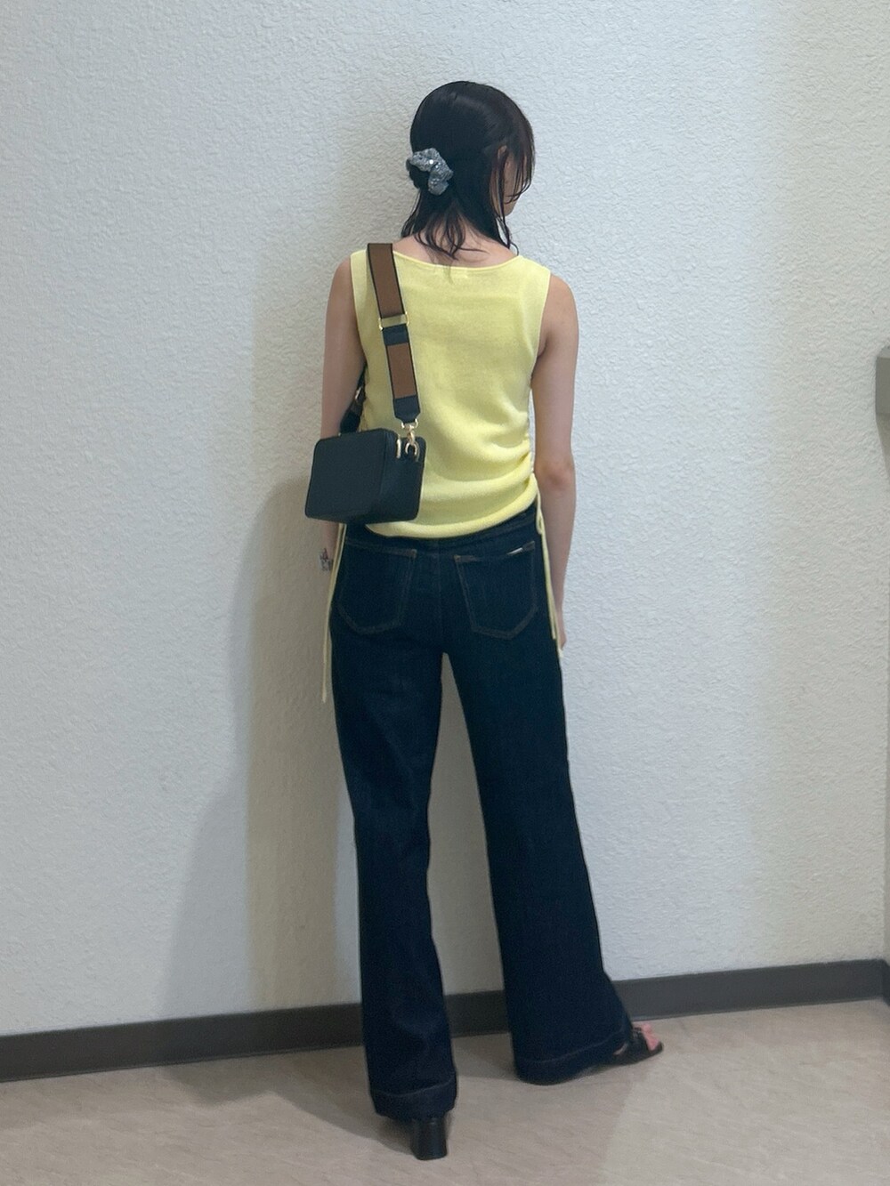 イエロー系のニット/セーター、ブルー系のデニムパンツ、ブラック系のショルダーバッグを着用したレディースの夏コーディネートの3枚目の写真