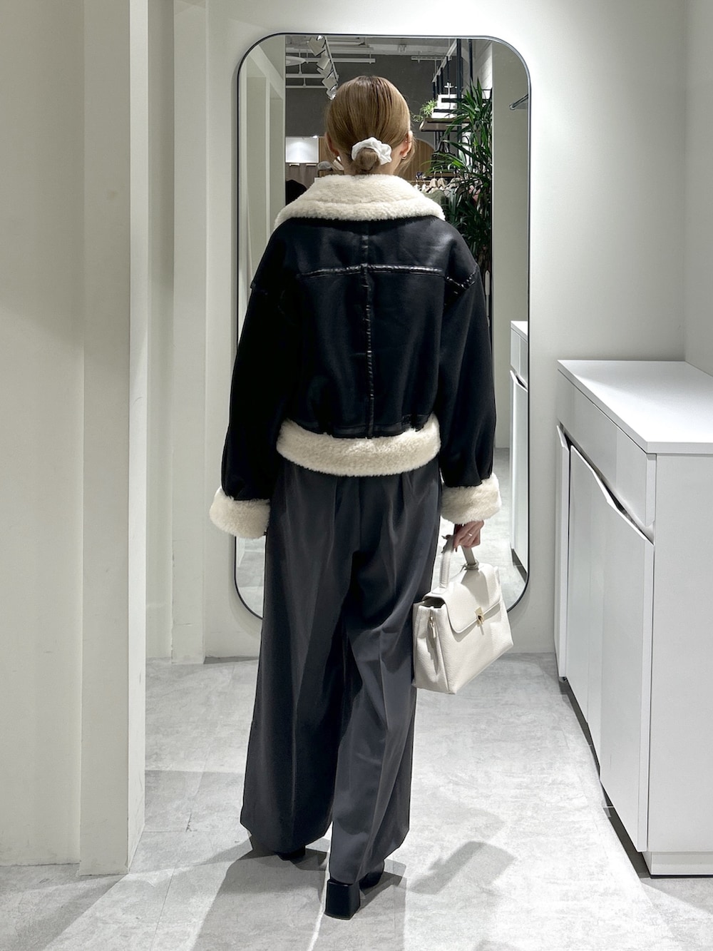 ブラック系のブルゾン、ブラック系のブーツ、グレー系のスラックスを着用したレディースの秋コーディネートの4枚目の写真