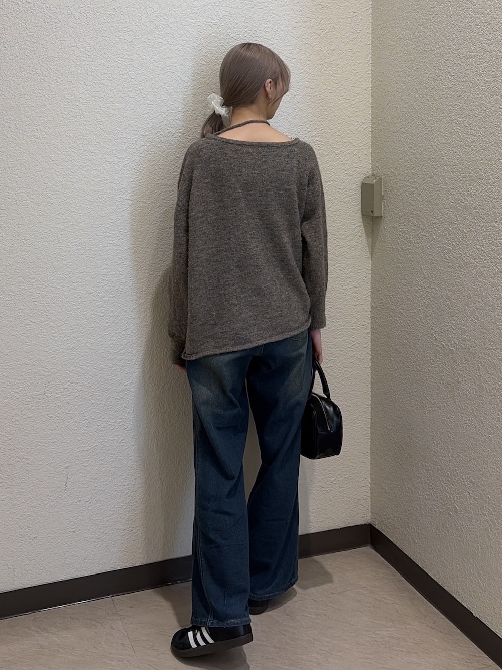 ブラウン系のニット/セーター、ブルー系のデニムパンツ、ブラック系のハンドバッグを着用したレディースの冬コーディネートの4枚目の写真