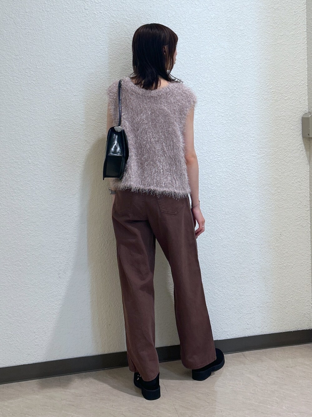 ブラウン系のデニムパンツ、ブラック系のショルダーバッグ、ベージュ系のニット/セーターを着用したレディースの夏コーディネートの3枚目の写真