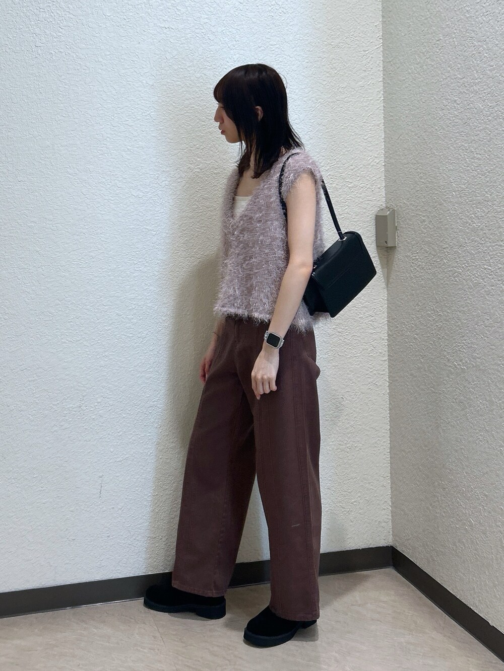 ブラウン系のデニムパンツ、ブラック系のショルダーバッグ、ベージュ系のニット/セーターを着用したレディースの夏コーディネートの2枚目の写真