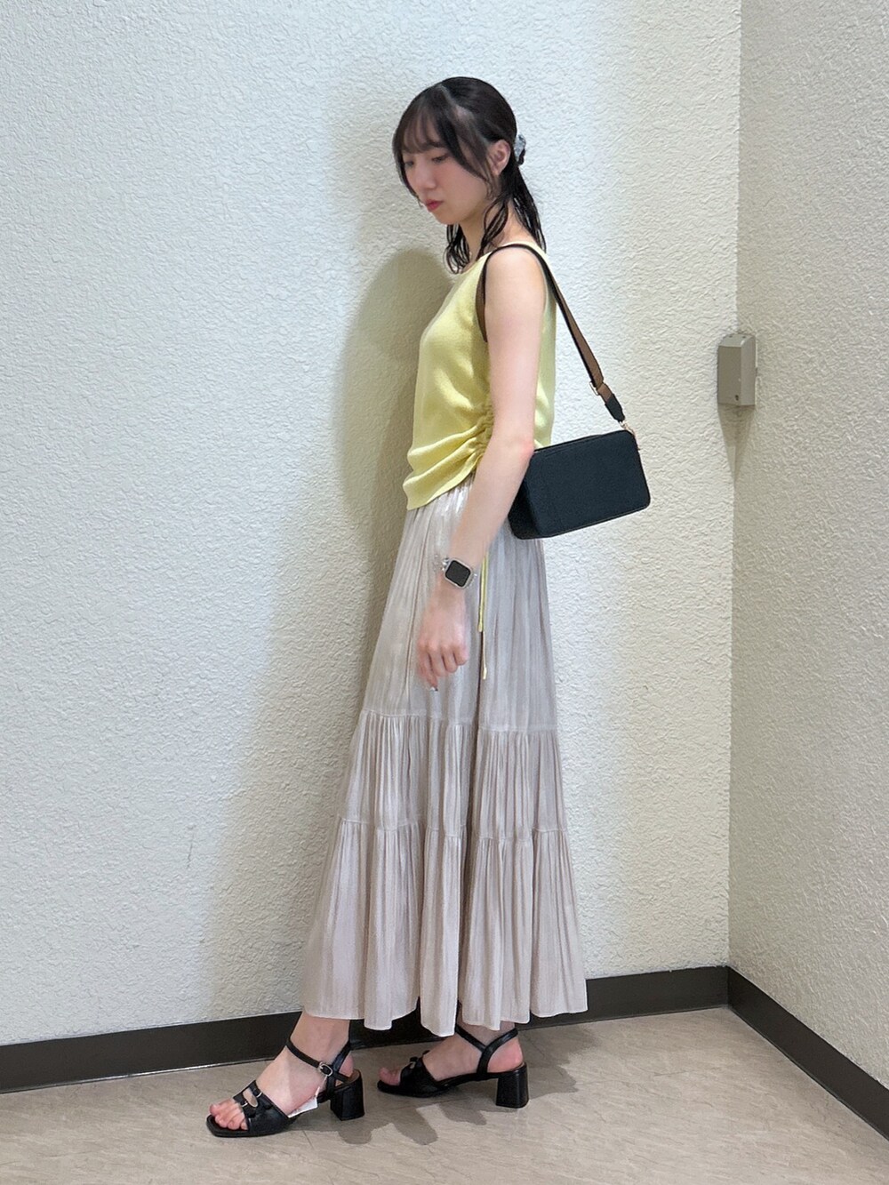 イエロー系のニット/セーター、ホワイト系のスカート、ブラック系のサンダルを着用したレディースの夏コーディネートの2枚目の写真