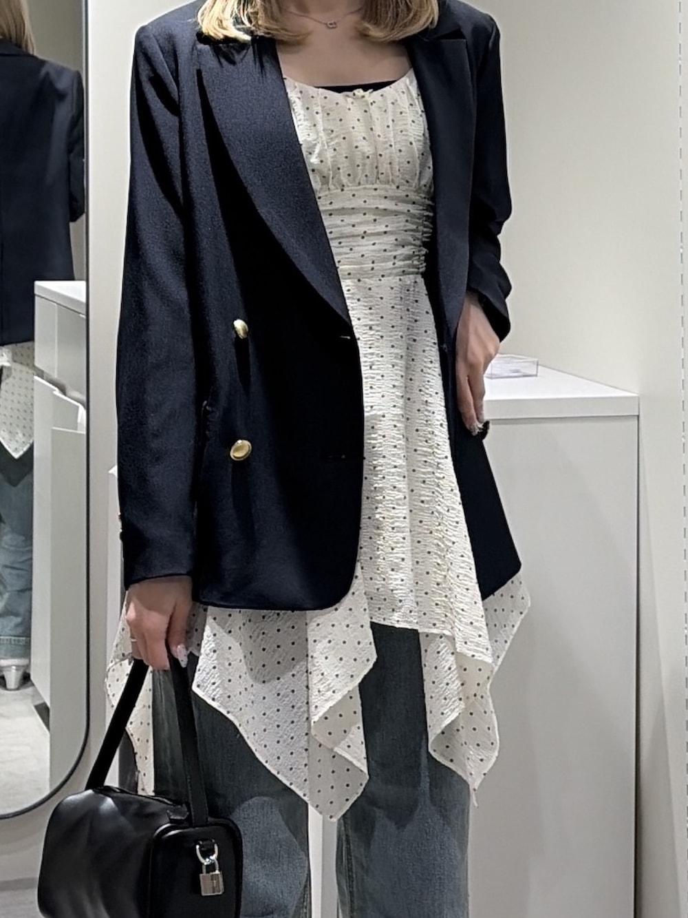 ホワイト系のワンピース、ブルー系のテーラードジャケット、ブルー系のデニムパンツを着用したレディースの春コーディネートの4枚目の写真