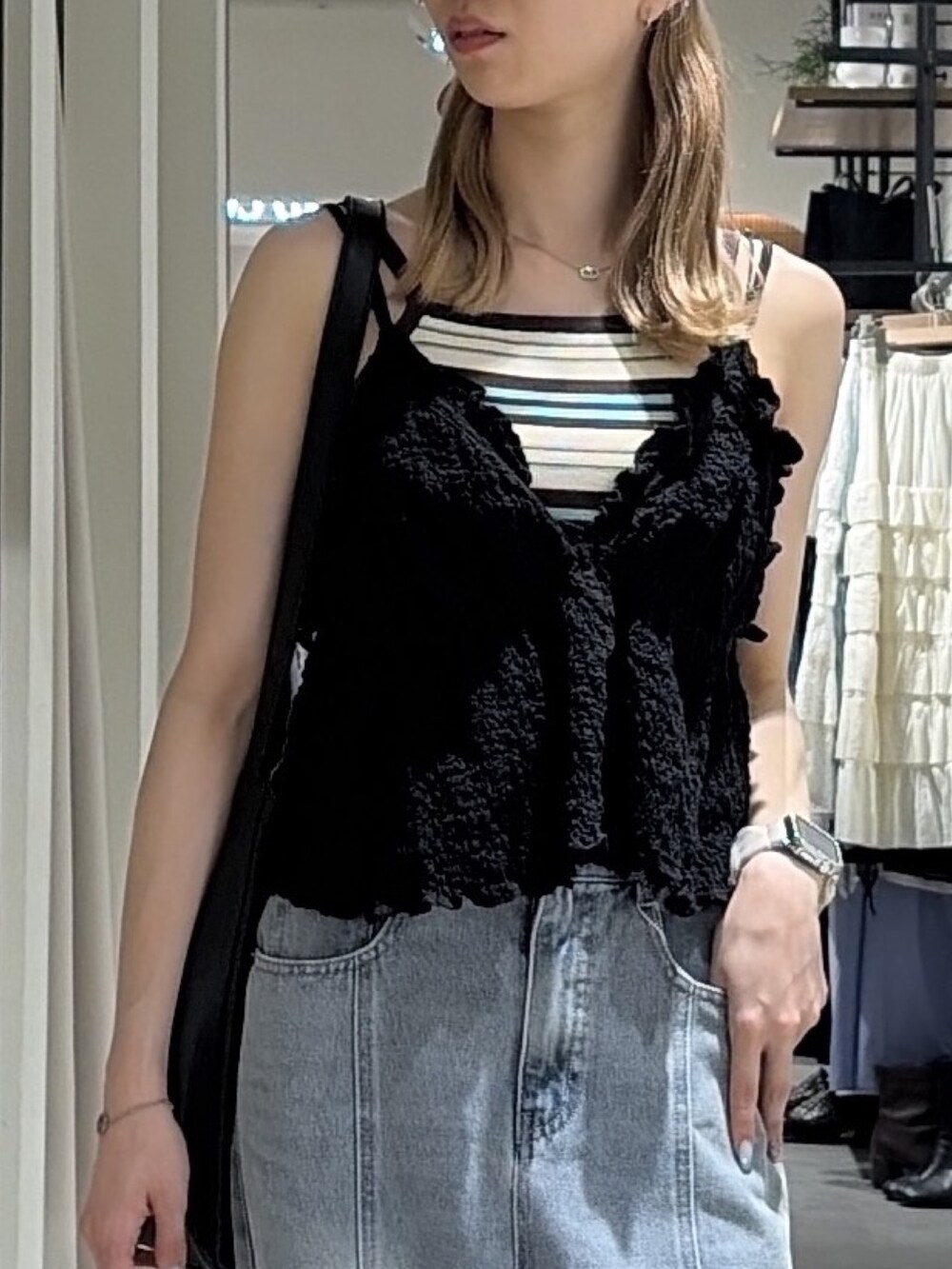 ブラック系のシャツ/ブラウス、ブルー系のニット/セーター、ブルー系のデニムパンツを着用したレディースの夏コーディネートの5枚目の写真