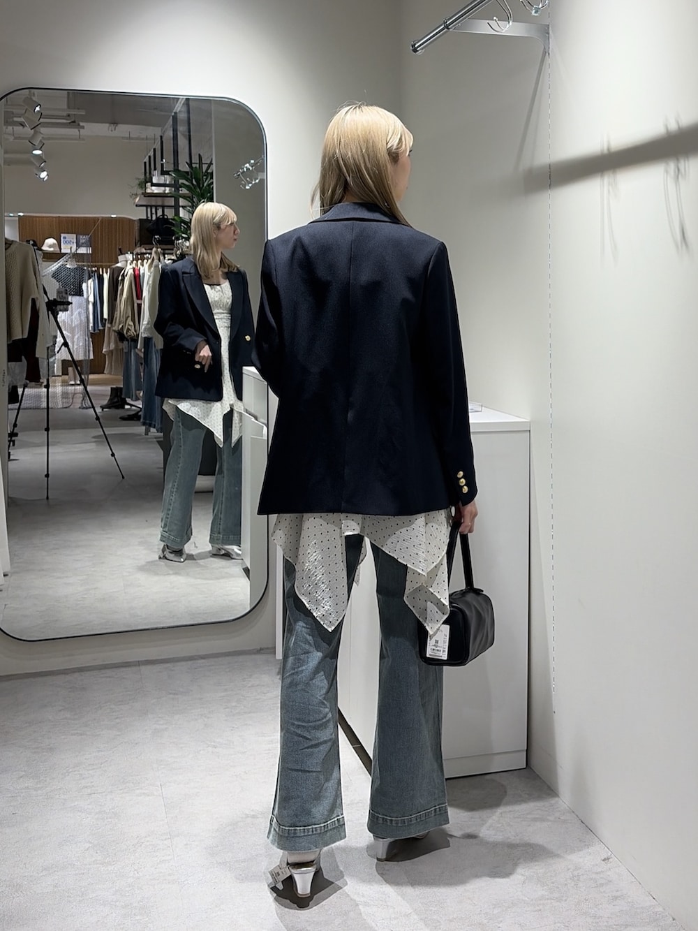 ホワイト系のワンピース、ブルー系のテーラードジャケット、ブルー系のデニムパンツを着用したレディースの春コーディネートの3枚目の写真