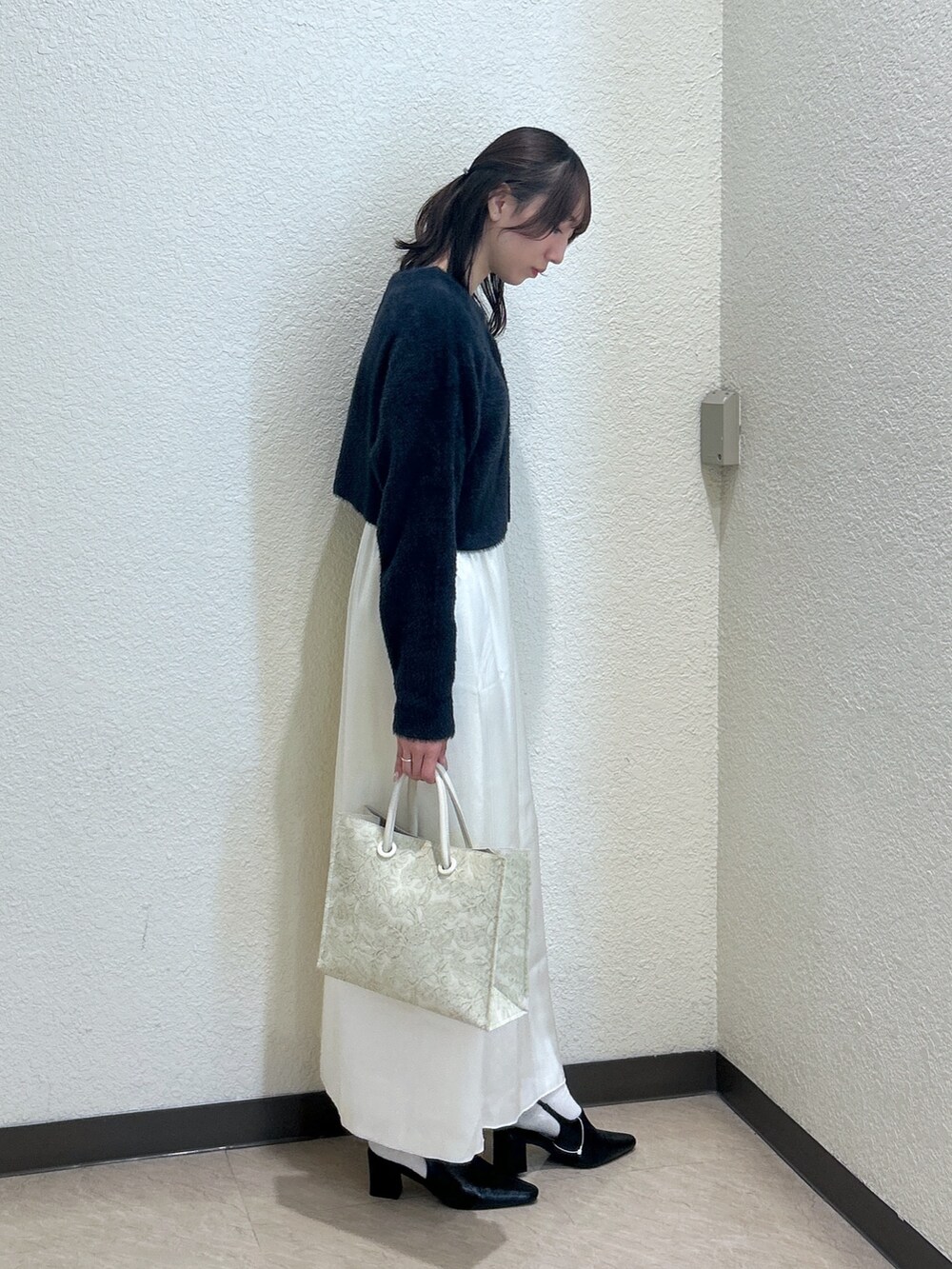ブルー系のニット/セーター、ホワイト系のスカート、ホワイト系のトートバッグを着用したレディースの秋コーディネートの4枚目の写真