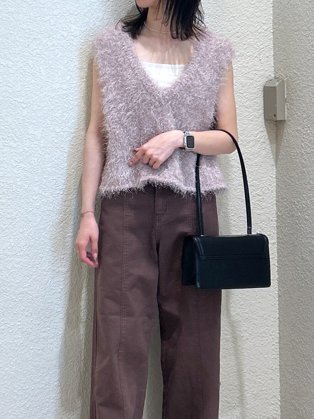 ブラウン系のデニムパンツ、ブラック系のショルダーバッグ、ベージュ系のニット/セーターを着用したレディースの夏コーディネートの4枚目の写真